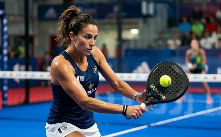 A female padel player in a blue tank top focusing on hitting a yellow ball with an Ianoni racket during a match.